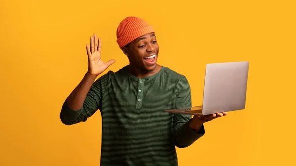 Alegre afro-americano cara fazendo chamada de vídeo com laptop, acenando a mão na câmera — Fotografia de Stock