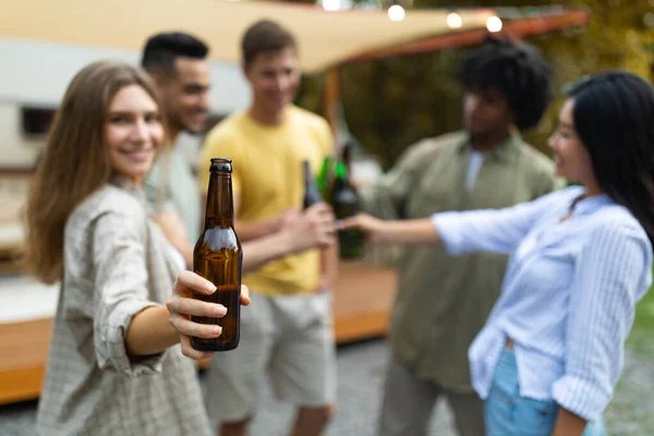 Kafkasyalı güzel bayan çeşitli arkadaşlarıyla bira şişeleriyle kadeh kaldırıyor, sonbaharda karavanın yanında alkol içiyor. — Stok fotoğraf