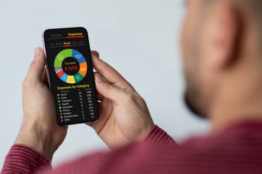 Cep telefonlu bir adam aylık aile harcamalarını hesaplıyor.