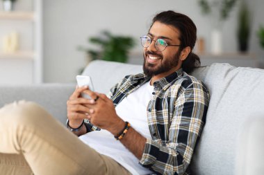 Yakışıklı Hintli adam evde akıllı telefonla oyun oynuyor.