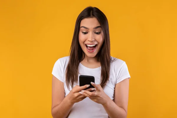 Happy enthousiast dame met behulp van mobiele telefoon in de studio — Stockfoto
