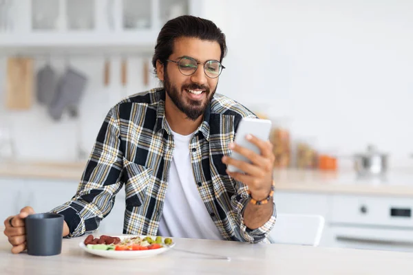 Sourire homme du Moyen-Orient manger des aliments sains et en utilisant le téléphone — Photo