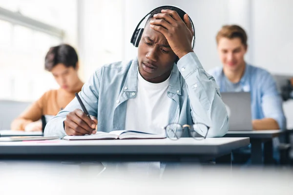 Geschokte zwarte student schrijven test zitten aan het bureau in de klas — Stockfoto