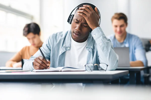 Sorprendido estudiante negro prueba de escritura sentado en el escritorio en clase — Foto de Stock