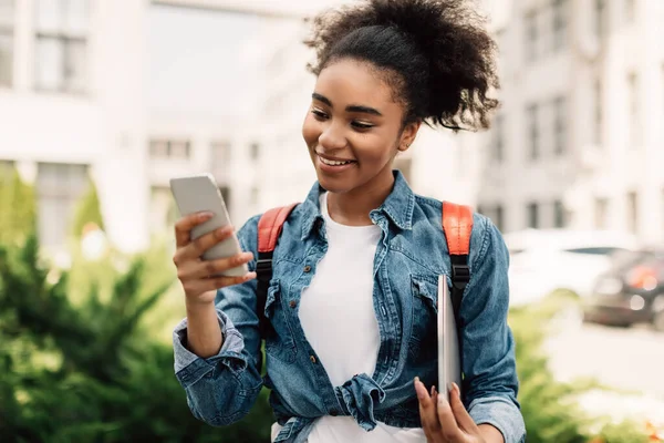 Gelukkig zwart college meisje met behulp van smartphone sms 'en buiten — Stockfoto