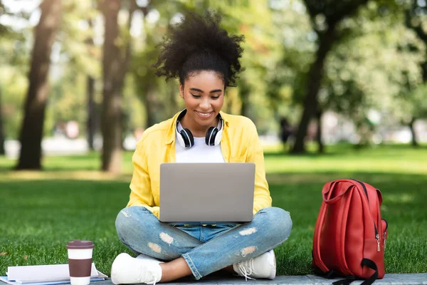 Afroamericano college ragazza utilizzando computer portatile seduta apprendimento in parco — Foto Stock