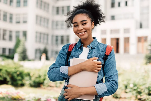 Felice afro-americano adolescente ragazza in posa vicino moderno università costruzione — Foto Stock