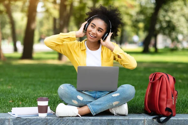 Feliz Chica Adolescente Usando Ordenador Portátil Usando Auriculares En Parque —  Fotos de Stock