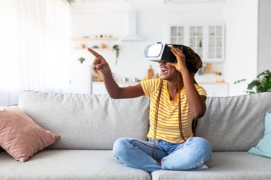 Milenyum siyahi kadın evde VR gözlük kullanıyor.