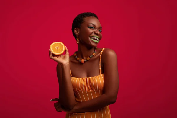 Extraordinary black woman holding half of orange and laughing — Stock Photo, Image