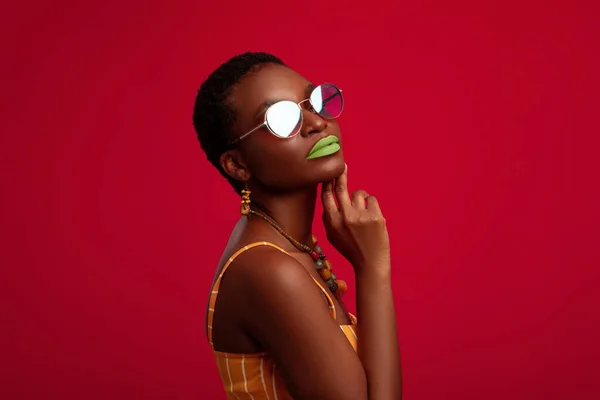 Black woman in summer outfit and glasses posing on red — Stock Photo, Image