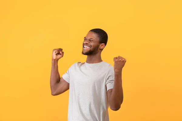 Triomfantelijke Afro-Amerikaanse man schreeuwend van opwinding, gebaren JA met beide handen over gele achtergrond — Stockfoto