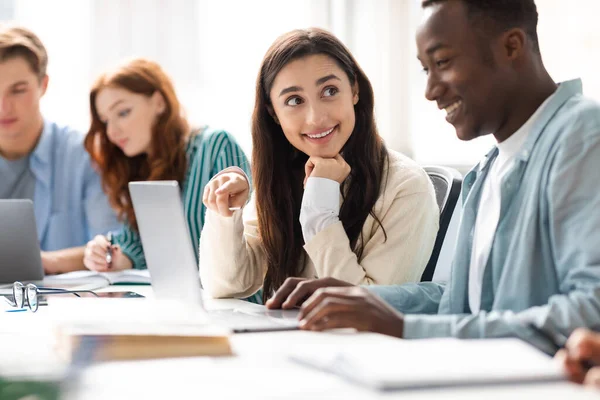 Sorrindo diversos estudantes sentados na mesa trabalhando em projeto de grupo — Fotografia de Stock