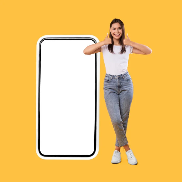 Femme montrant écran blanc vide smartphone et pouces vers le haut — Photo