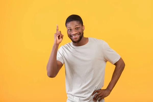 Ich habe eine Idee. Inspiriert afrikanisch-amerikanischer Mann hebt den Finger, steht über gelbem Studiohintergrund — Stockfoto