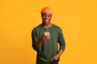 Güzel uygulama. Akıllı telefon kullanan mutlu genç siyah adam, yeni uygulamalara göz atıyor