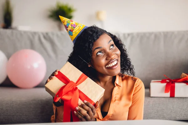 Zwarte vrouw die een verjaardagscadeau vasthoudt. Raad eens wat erin zit. — Stockfoto