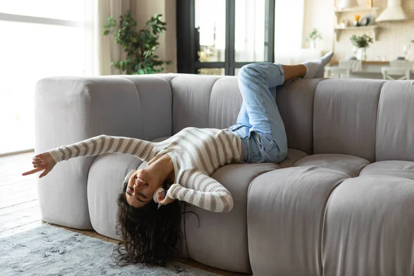 Joyeux jeune femme dans un casque couché sur le canapé et écoutant de la musique, relaxant à la maison, pleine longueur — Photo