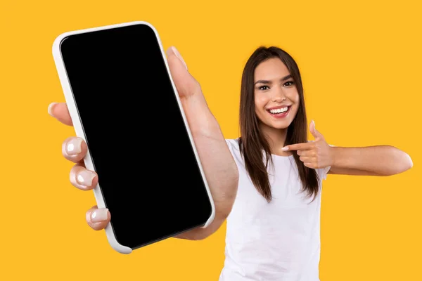 Mulher mostrando branco tela do smartphone vazio e apontando — Fotografia de Stock