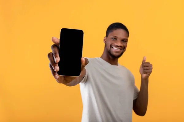 Fröhlicher afrikanisch-amerikanischer Mann demonstriert Smartphone mit leerem Bildschirm, zeigt Kopierplatz für Ihre Anzeige oder Ihr Design — Stockfoto