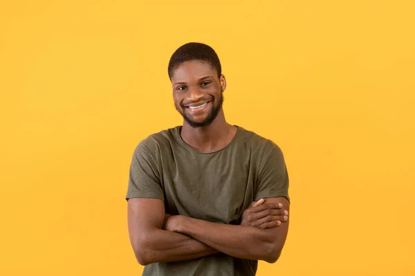 Männerporträt. Glücklicher afrikanisch-amerikanischer Typ mit verschränkten Armen, der in die Kamera lächelt und vor gelbem Hintergrund posiert — Stockfoto
