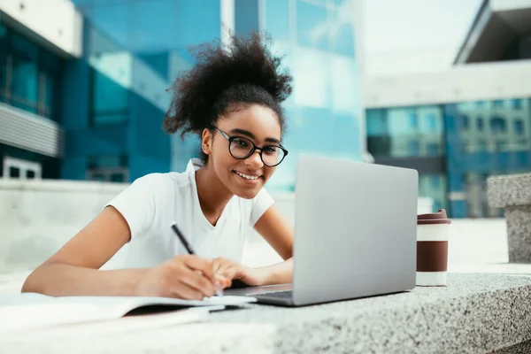 Allegro africano studente ragazza prendere appunti a computer portatile all'aperto — Foto Stock