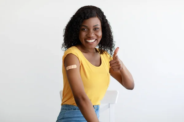 Gevaccineerde Afrikaanse Dame Gesturing Duimen-Up Toont Arm Vaccinatie In Studio — Stockfoto