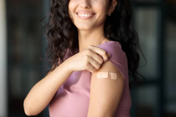 Coronavirus prevention. Unrecognizable female patient showing arm with band aid after corona vaccine injection at home — Stock Photo, Image