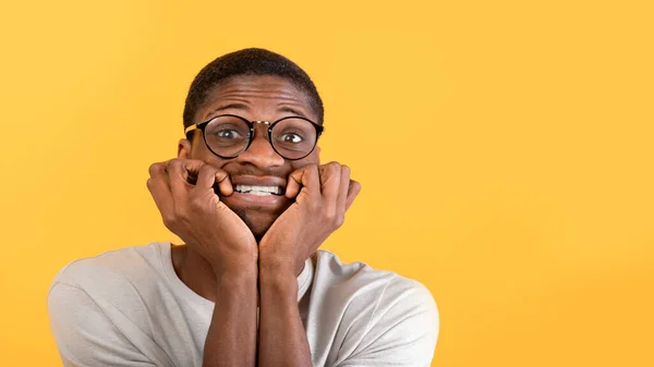 Stressbeheersingsconcept. Bang zwarte man bijten nagels met zorg, kijken naar camera over gele achtergrond, panorama — Stockfoto