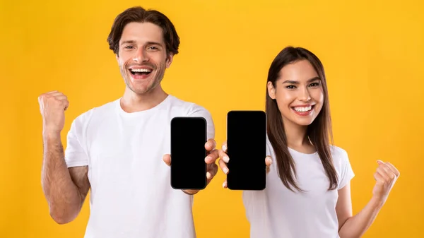 Pareja mostrando dos pantallas de teléfonos inteligentes vacías haciendo un gesto sí — Foto de Stock