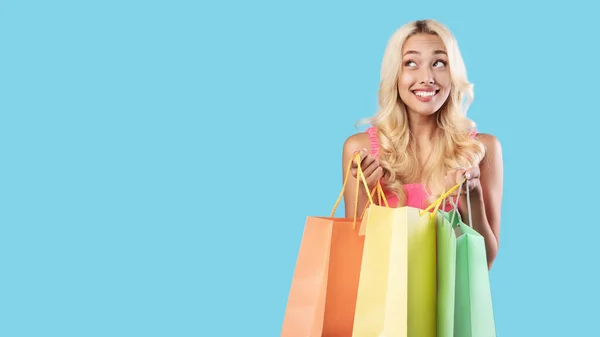 Mulher excitada segurando sacos de compras coloridos olhando para longe — Fotografia de Stock