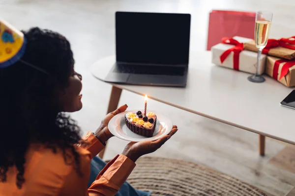 African American Woman på laptop håller födelsedagstårta inomhus, Bakåt — Stockfoto