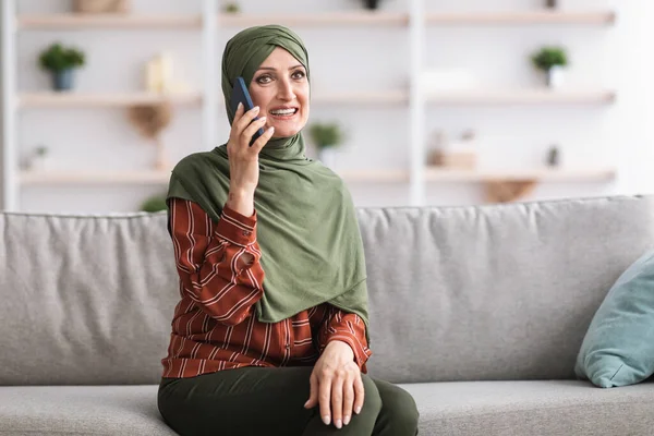 Happy Middle-Aged Islamic Woman In Hijab Talking On Cellphone Indoor (dalam bahasa Inggris). — Stok Foto