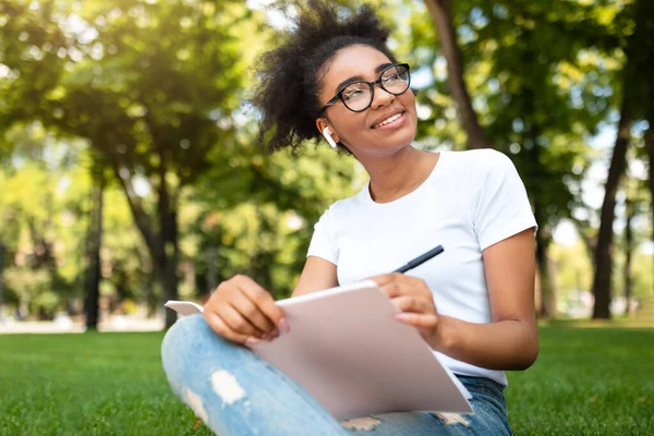 Gülümseyen Siyahi Öğrenci Kız Çizim yapıyor Dışarıda Park 'ta oturuyor — Stok fotoğraf