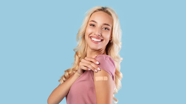 Mujer vacunada feliz mostrando vendaje adhesivo después de la vacuna —  Fotos de Stock