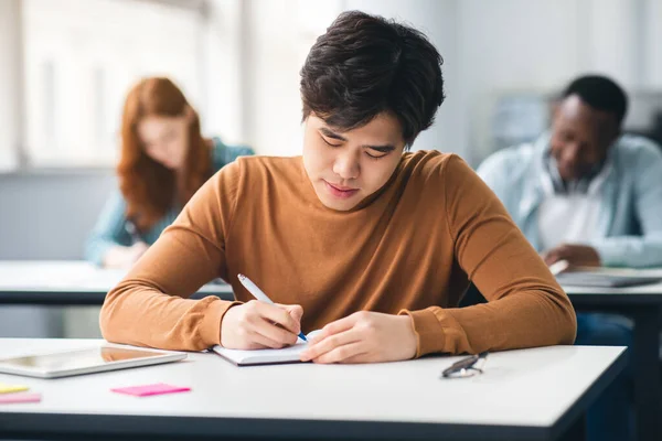 Asiática estudiante sentado en escritorio en aula escritura en portátil — Foto de Stock