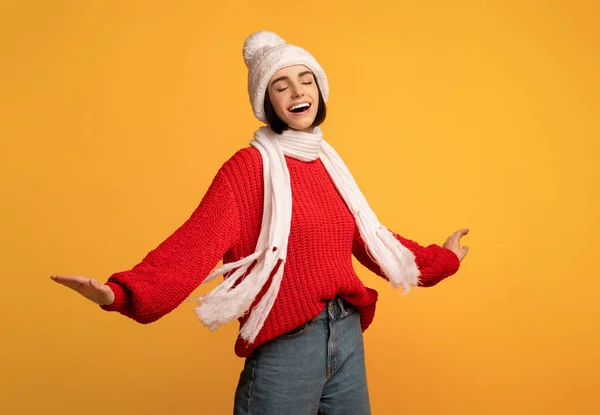 白いニットの冬のセットと赤いセーターのダンスでケアフリー遊び心のある女性と黄色の背景に回って — ストック写真