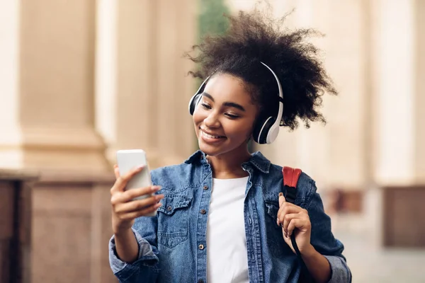 Afro-américaine étudiant fille à l'aide téléphone portant casque marche en plein air — Photo