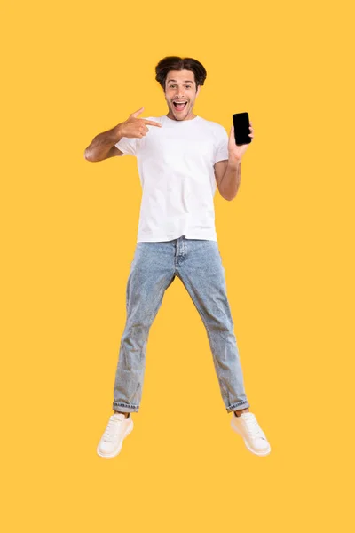 Hombre mostrando blanco pantalla vacía del teléfono inteligente y saltar —  Fotos de Stock