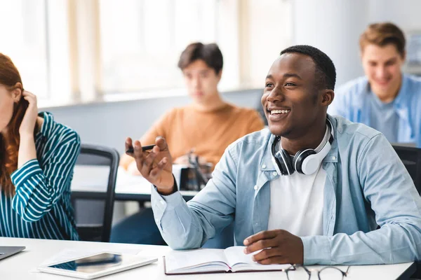 Estudiante negro sonriente hablando con el profesor en el aula — Foto de Stock