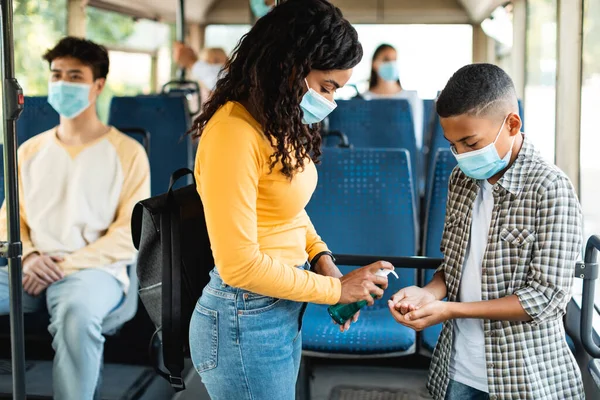 Mujer negra viajando con un niño, usando desinfectante en el autobús —  Fotos de Stock