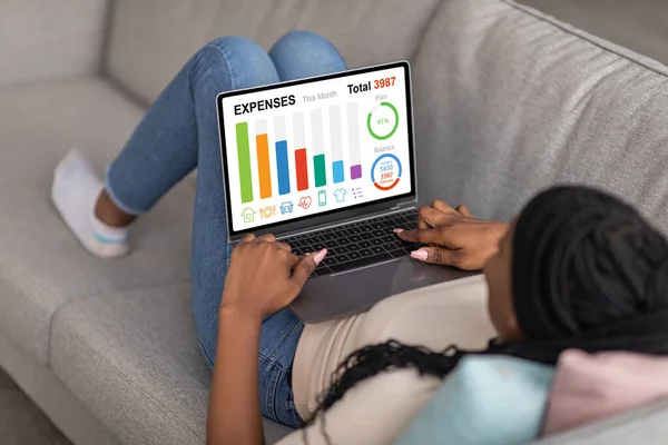 Mujer afroamericana usando laptop, revisando sus gastos — Foto de Stock