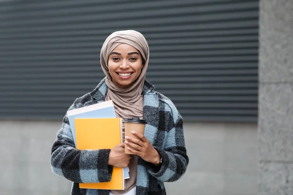 Joven estudiante sonriendo a la cámara, sosteniendo la carpeta en la ciudad — Foto de Stock