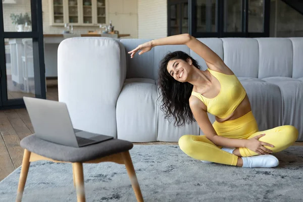 Dizüstü bilgisayarın önünde yoga yapan formda genç bir kadın, antreman sırasında eğilme, yer kopyalama... — Stok fotoğraf