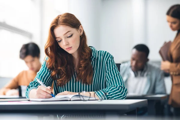 Estudiante diligente sentado en el escritorio en el aula posando ante la cámara — Foto de Stock