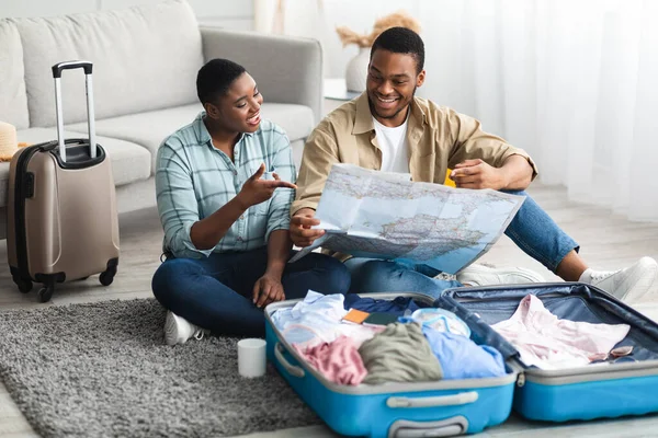 Cónyuges Negros celebrando mapa turístico Elegir país para vacaciones en interiores — Foto de Stock