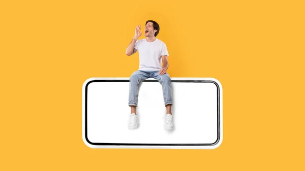 Guy assis sur l'écran blanc vide du smartphone et faire une annonce — Photo