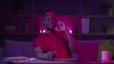 Cep telefonuyla konuşan mutlu siyah adam evde oturuyor.