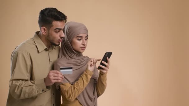 クレジットカードやスマートフォンのオンラインショッピングを使用してイスラム教徒のカップル,スタジオ — ストック動画