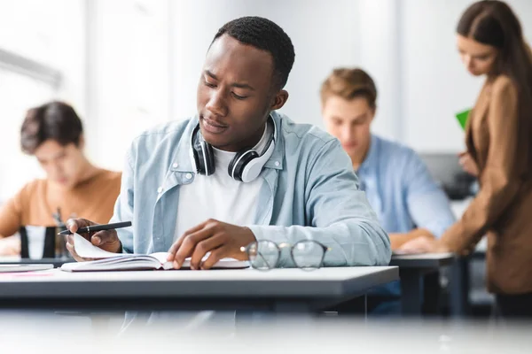 Svart man sitter vid skrivbordet skriva examen, läsa uppgifter — Stockfoto